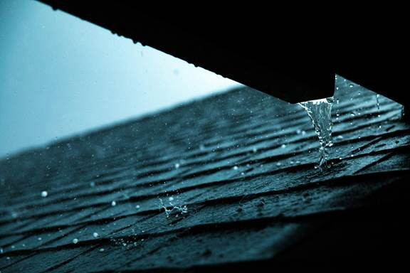 Rainwater running across roof shingles, highlighting the need for roof leak repair in California