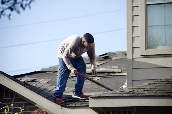 Roofing contractor inspecting shingle damage before roof repair